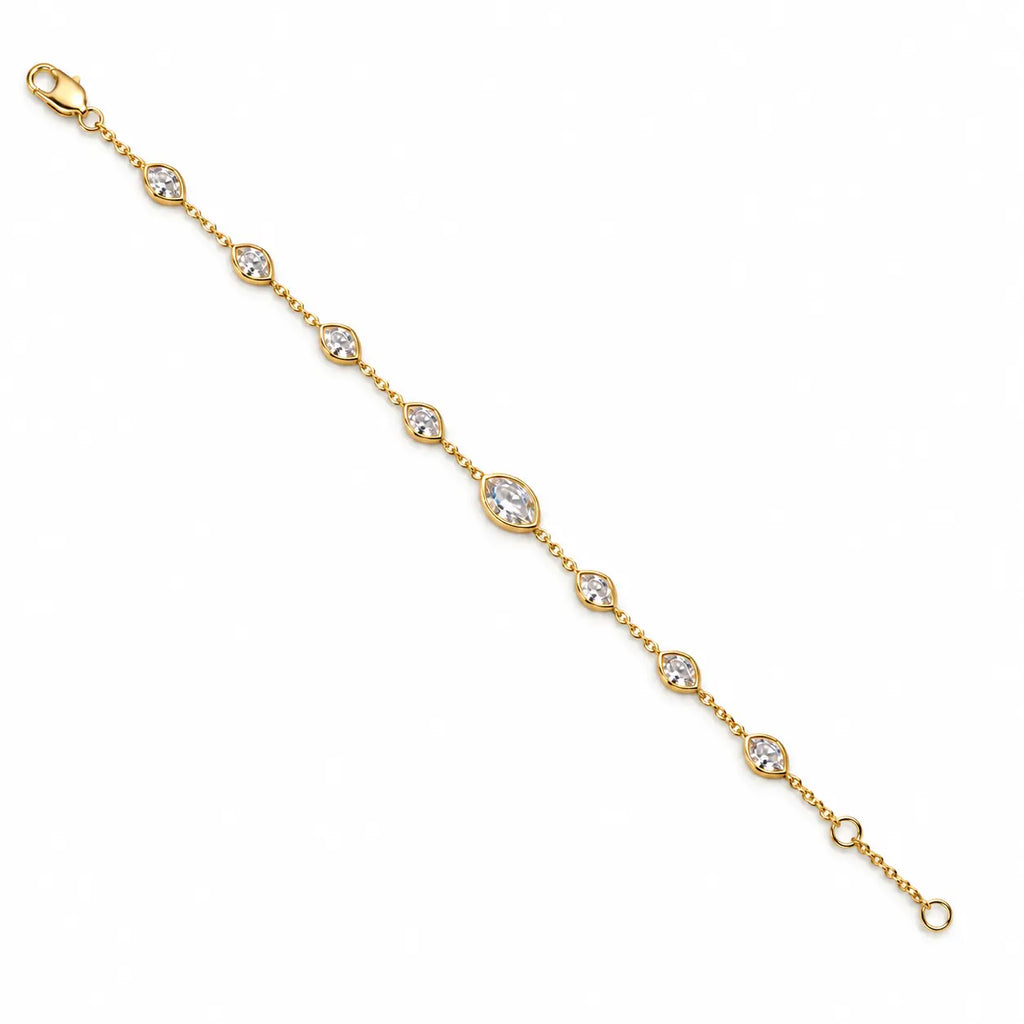 A delicate yellow gold chain bracelet with multiple marquise-cut clear stones, laid flat on a white marble background.