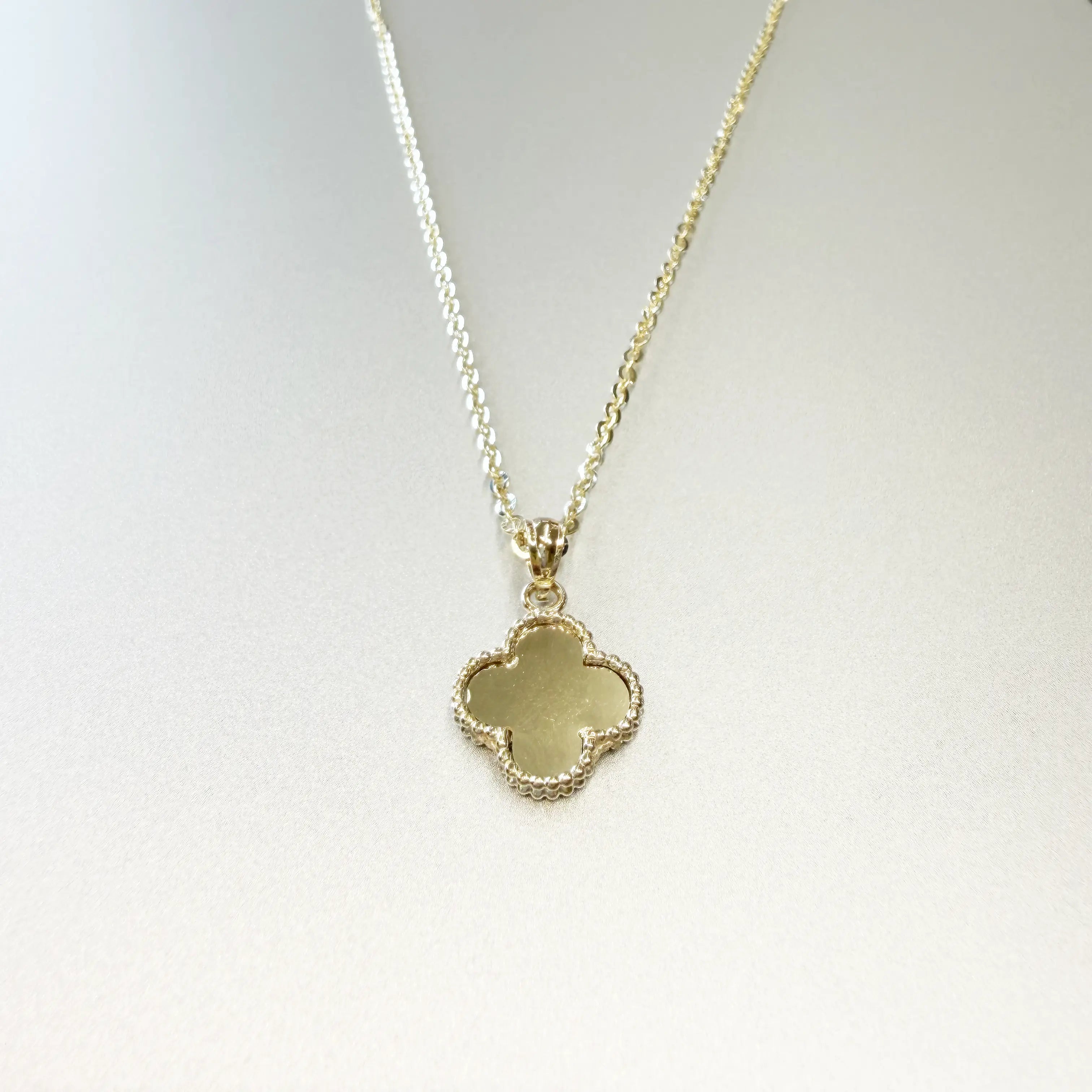 14K yellow gold four-leaf clover necklace showing smooth polished gold back face with milgrain beaded border on display bust